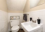 Thumbnail 9 of 21 - A white toilet and sink in a small bathroom.