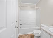 Thumbnail 15 of 20 - A white bathroom with a toilet, sink, and bathtub.