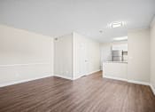 Thumbnail 2 of 20 - A room with wood flooring and a refrigerator.