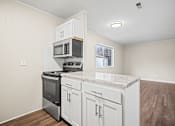 Thumbnail 9 of 20 - A kitchen with a granite countertop and white cabinets.