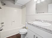 Thumbnail 11 of 20 - A white bathroom with a toilet, sink, and bathtub.