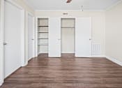 Thumbnail 10 of 20 - A room with white doors and a brown floor.