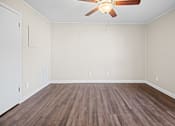 Thumbnail 6 of 20 - A room with a ceiling fan and wooden flooring.