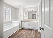 Thumbnail 17 of 22 - A white bathroom with a tub, sink, and mirror.