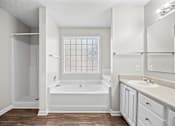 Thumbnail 15 of 22 - A white bathroom with a tub, sink, and mirror.
