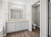 Thumbnail 16 of 22 - A white bathroom with a wooden floor and a white tub.