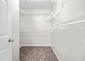 Thumbnail 18 of 22 - A white closet with a carpeted floor and white shelves.