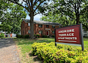 Thumbnail 1 of 14 - a red brick apartment building with a red sign in front of it