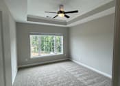 Thumbnail 4 of 18 - A bedroom in an apartment with a ceiling fan and a window looking out to Clayton, NC.