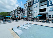 Thumbnail 2 of 45 - a swimming pool with chaise lounge chairs and umbrellas in front of an apartment building in Asheville