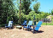 Thumbnail 27 of 51 - A group of blue chairs are arranged in a circle on a gravel area.