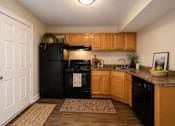 Thumbnail 6 of 21 - A kitchen with wooden cabinets and black appliances.