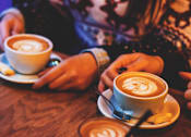 Thumbnail 20 of 21 - Two cups of coffee with latte art on a wooden table.