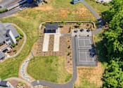 Thumbnail 12 of 29 - A tennis court is surrounded by a grassy area and a few trees.