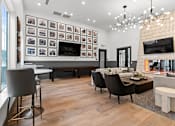 Thumbnail 5 of 19 - A modern living room with a large TV and a long table with chairs.