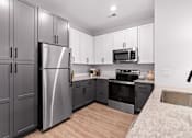Thumbnail 11 of 19 - A modern kitchen with a stainless steel refrigerator and microwave above the oven.