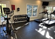 Thumbnail 10 of 23 - A gym with treadmills, elliptical machines, and dumbbells.