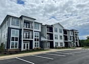 Thumbnail 15 of 25 - Garden-Style Apartments In Weaverville, NC - Highline North - Parking Lot In Front Of Apartment Building Surrounded By Greenery