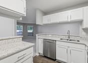 Thumbnail 9 of 29 - A kitchen with white cabinets and a granite countertop.