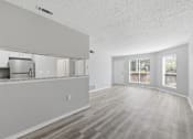 Thumbnail 8 of 29 - A spacious room with wooden flooring and white walls.