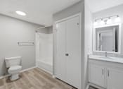 Thumbnail 16 of 29 - A white bathroom with a toilet, sink, and mirror.