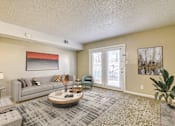 Thumbnail 4 of 13 - A living room with a grey couch, a coffee table, and a painting on the wall.