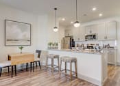 Thumbnail 1 of 25 - A kitchen with a table and chairs and a framed picture on the wall.