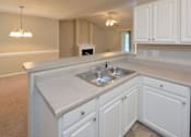 Thumbnail 4 of 9 - A kitchen with white cabinets and a sink.