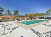 Thumbnail 11 of 13 - A pool surrounded by sun loungers and a building in the background.
