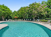 Thumbnail 16 of 46 - A swimming pool surrounded by trees and chairs.