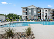 Thumbnail 2 of 31 - A large apartment complex with a pool in front.
