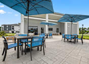 Thumbnail 3 of 31 - A patio with tables and chairs under umbrellas.