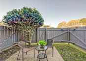 Thumbnail 9 of 13 - A backyard with a table and chairs and a tree.