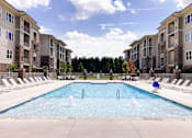 Thumbnail 2 of 21 - A large swimming pool in front of apartment buildings.