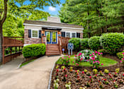 Thumbnail 20 of 21 - A small house with a blue door is surrounded by a garden.