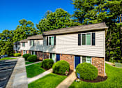 Thumbnail 1 of 21 - A row of houses with green bushes in front.