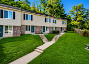 Thumbnail 2 of 21 - A grassy area in front of a building with a concrete pathway.