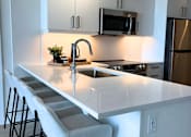 Thumbnail 9 of 12 - A kitchen with a white countertop and a stainless steel refrigerator.