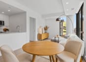 Thumbnail 14 of 59 - a living room with a wooden table and a kitchen in the background