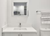 Thumbnail 33 of 46 - a white bathroom with a sink toilet and mirror