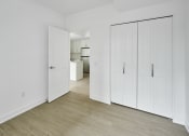 Thumbnail 43 of 46 - a bedroom with white walls and white closets and a wood floor