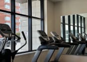 Thumbnail 20 of 21 - a gym with cardio machines and large windows
