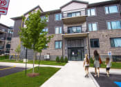 Thumbnail 2 of 11 - people walking in front of an apartment building
