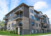 Thumbnail 1 of 11 - a brick apartment building with balconies on a sunny day