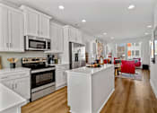 Thumbnail 10 of 19 - A modern kitchen with white cabinets and stainless steel appliances.