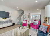 Thumbnail 8 of 38 - A living room with a white sofa and a pink armchair.