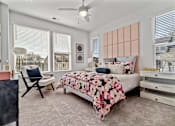 Thumbnail 8 of 19 - A bedroom with a bed, chair, and a ceiling fan.