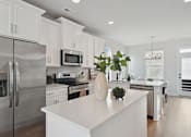 Thumbnail 18 of 19 - A modern kitchen with a stainless steel refrigerator and white cabinets.