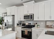 Thumbnail 17 of 19 - A modern kitchen with white cabinets and stainless steel appliances.