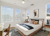 Thumbnail 13 of 19 - A bedroom with a bed, chair, and window with blinds.